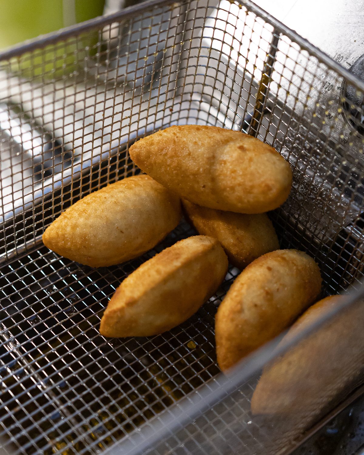 Rissóis in a fryer basket, golden and fresh, Porto restaurant kitchen