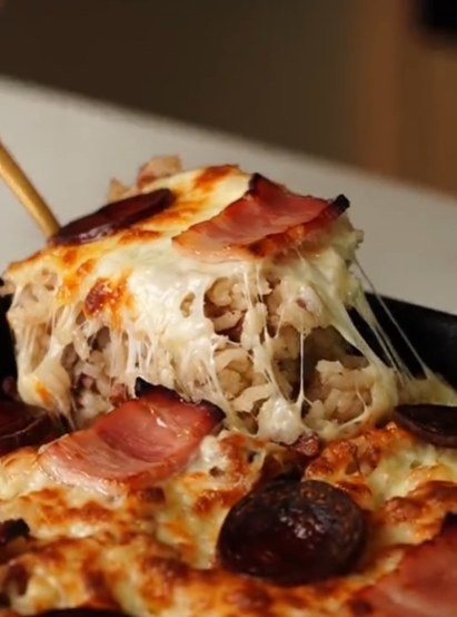 Duck rice with a toasted cheese crust being lifted with a spoon